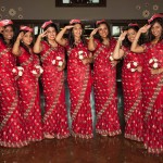 All in red dresses holding red and white flowers